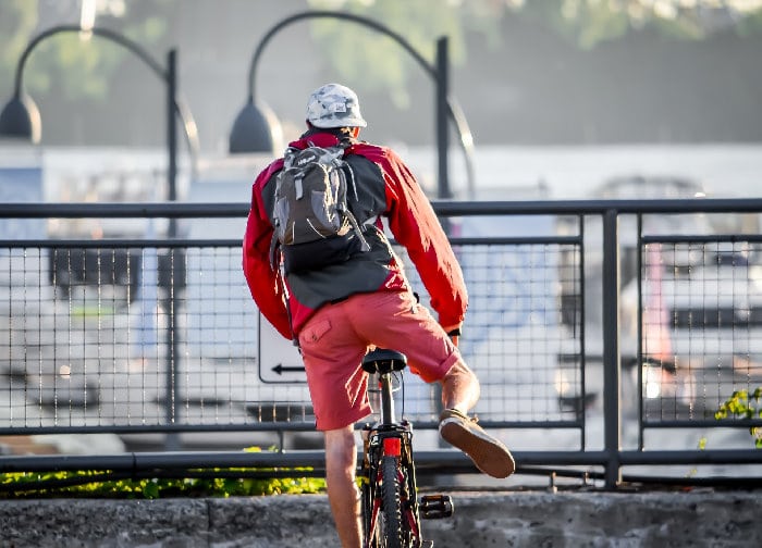 male cyclist with bike commuter backpack sitting on the bicycle