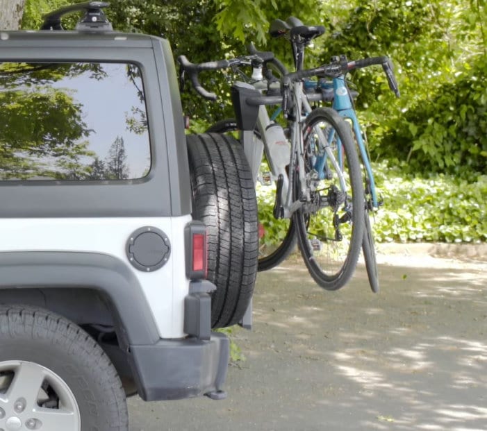 grey jeep wrangler with attached Yakima spare tire bike rack and two bicycles