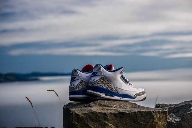 pair of white-and-blue Air Jordan 2's on rock fragment 