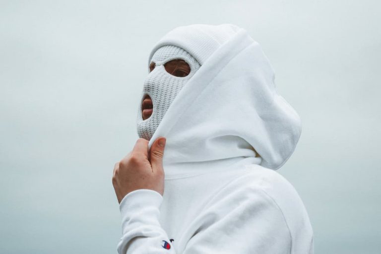 man in white hoodie and white balaclava preparing for bicycle ride in winter