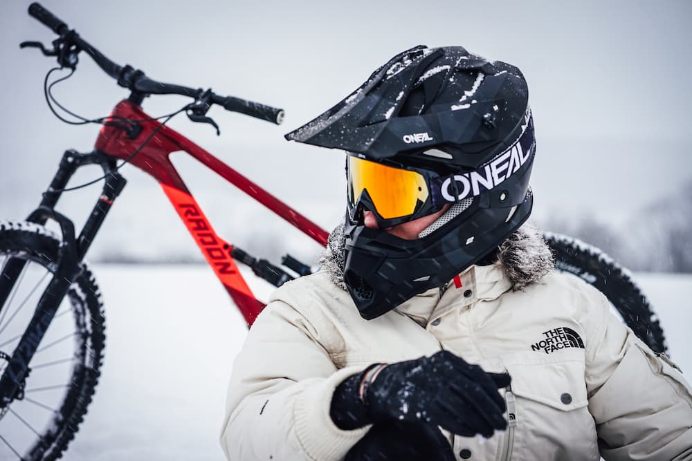 winter cyclist in helmet relaxing in snow