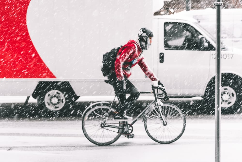 man riding a bike during a winter snowstorm