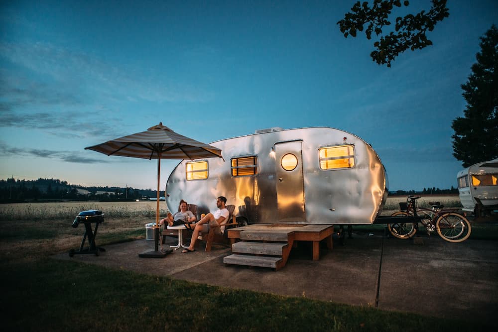 family relaxing at their travel trailer with bicycles nearby