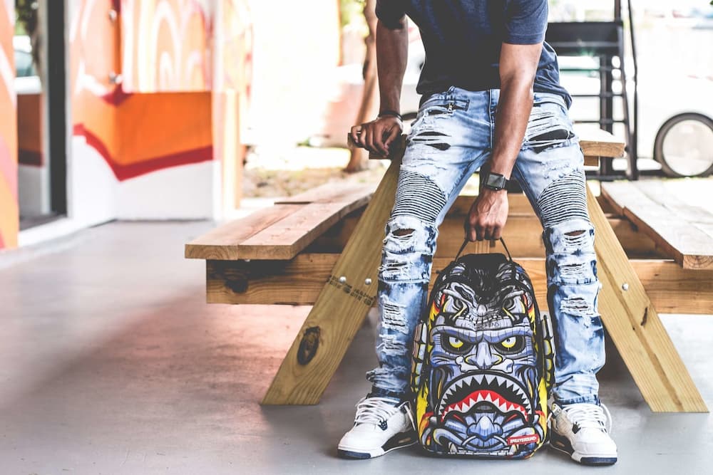 young cyclist holding backpack with face print