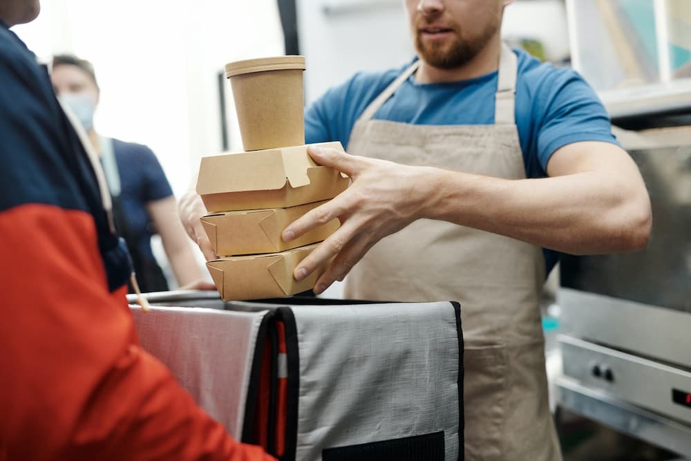 cook placing food in insulated bag for bike delivery