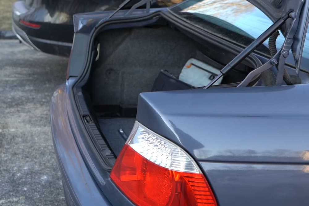 dark blue BMW E46 3 series with open trunk waiting for a bicycle to be loaded in