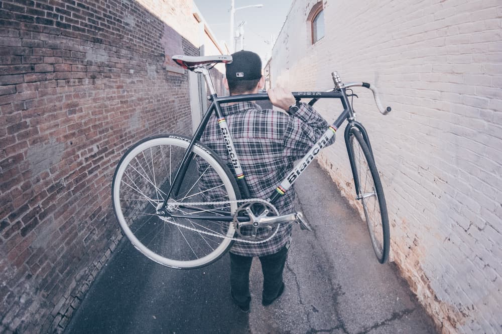 cyclist carrying bicycle on his back