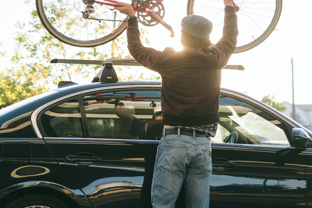 man securing a bike on the roof rack for a high speed drive